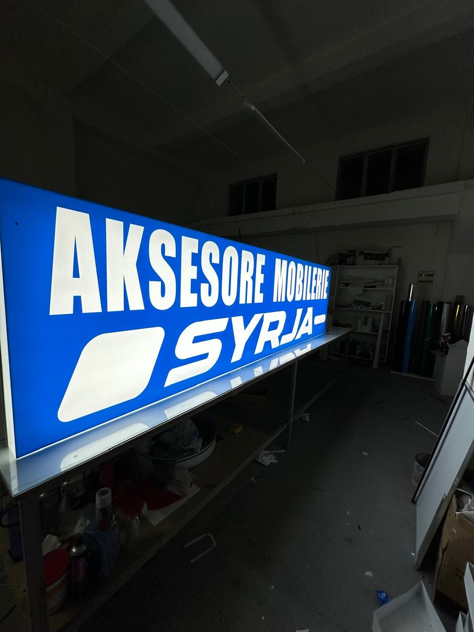Long blue Aksesore Mobilerie Syrja lightbox glowing on the studio bench in the dark