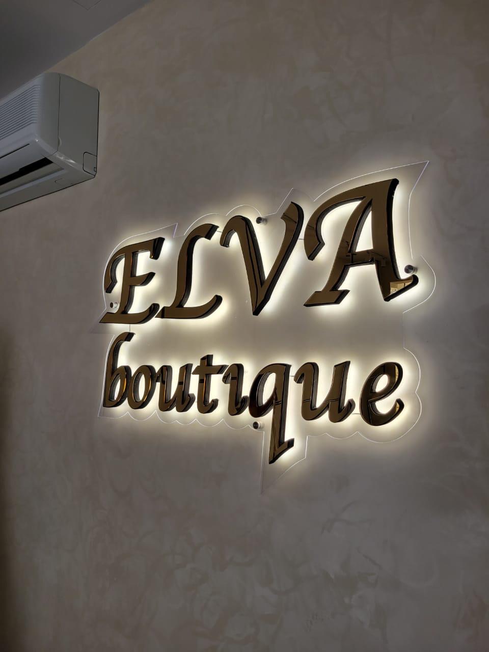 Mirror-gold ELVA boutique letters with warm halo lighting on the shop wall