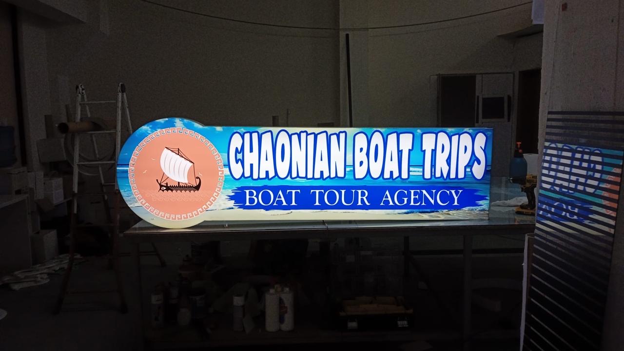 Chaonian Boat Trips lightbox with an ancient trireme and blue sea, lit on the studio bench
