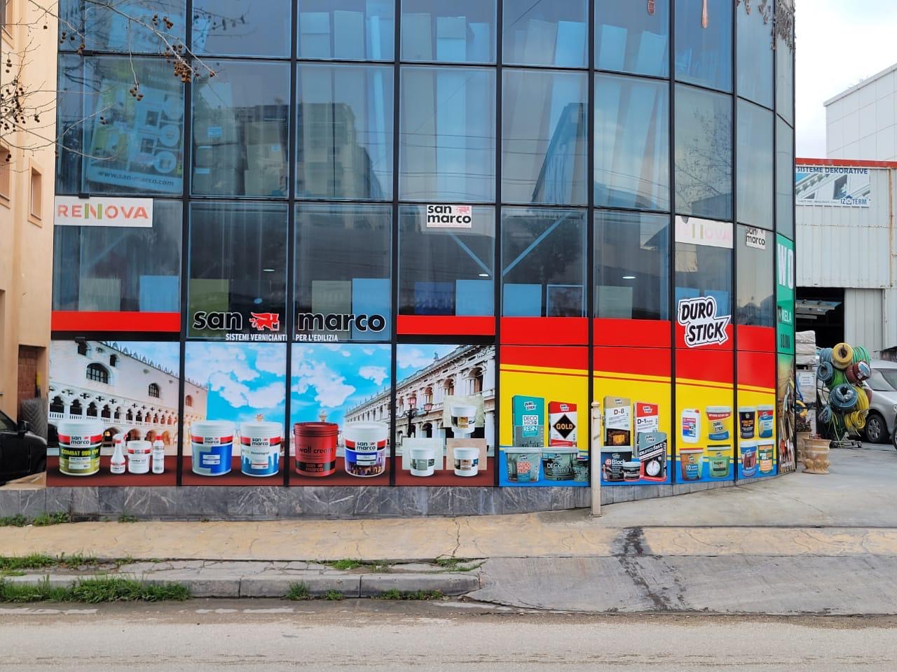 Curved glass facade with a San Marco and Duro Stick graphics band showing paint products