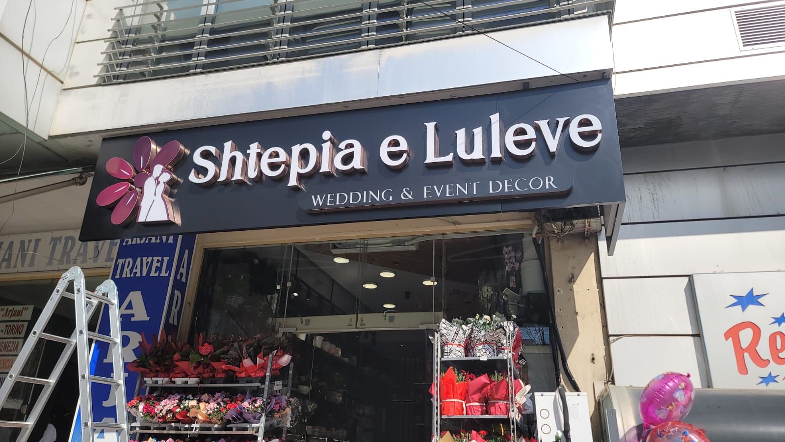 White 3D letters and a magenta flower logo above the flower shop entrance